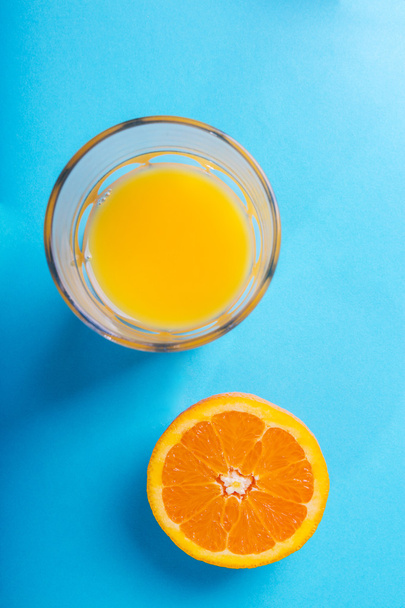 Glass of orange juice and half of orange - Foto, afbeelding