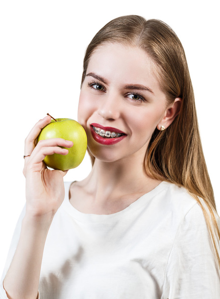 Young woman with brackets on teeth eating apple - Foto, imagen