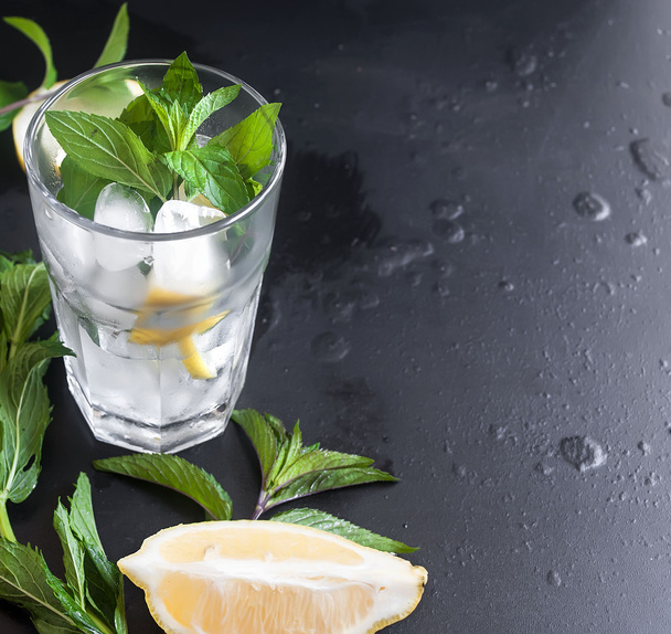 glasses with ice and lemon, mint and ice on a black background - Foto, afbeelding