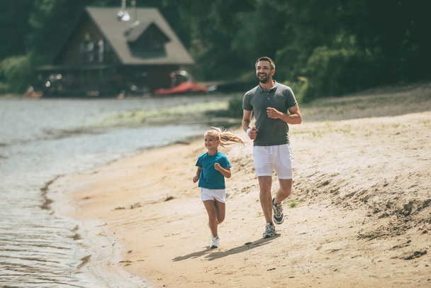 Otec a dcera zaběhat na břehu řeky  - Fotografie, Obrázek