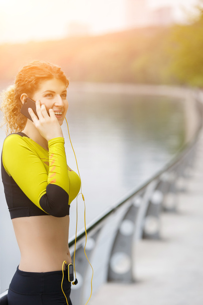 Happy sporty girl talking on phone in park - Foto, Imagen
