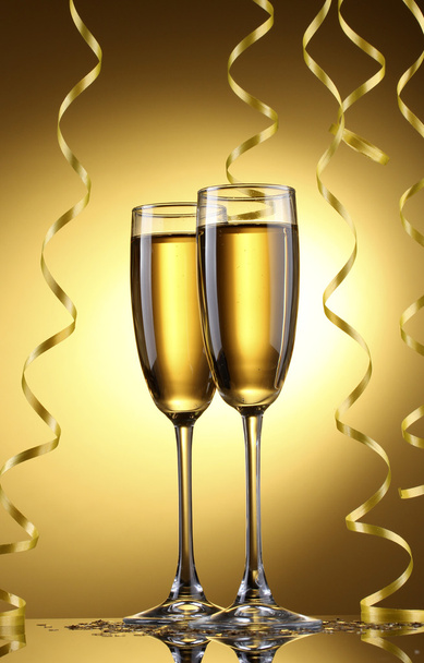 Glasses of champagne and streamer on yellow background - Foto, Bild