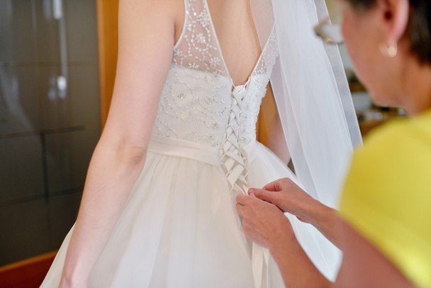 Bridesmaid is lacing wedding dress - Foto, imagen