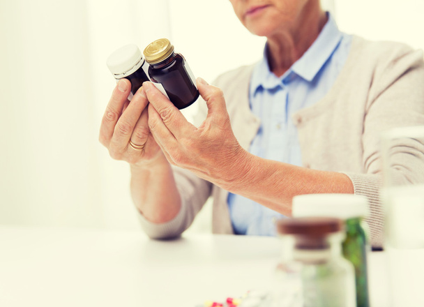 close up of senior woman with medicine jars - Foto, imagen