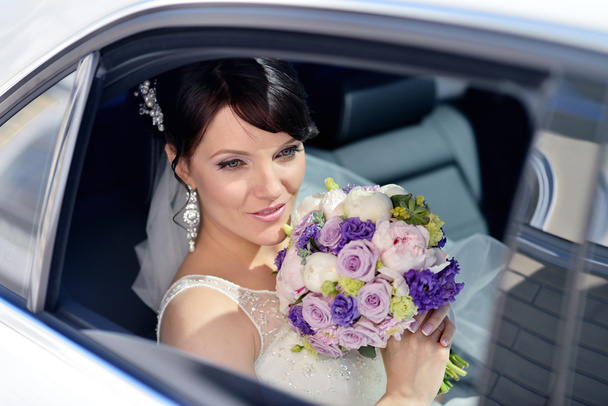bride with bouquet and lace veil in car - Foto, Bild