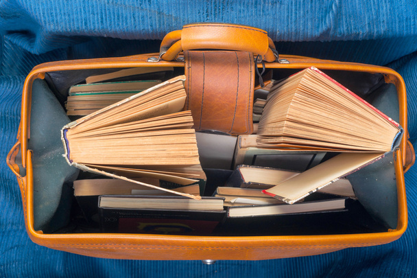 Стопка книг в твёрдом переплете в старом чемодане с
. - Фото, изображение