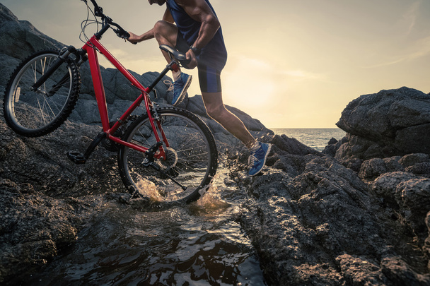 Homem carregando uma bicicleta na rocha
 - Foto, Imagem
