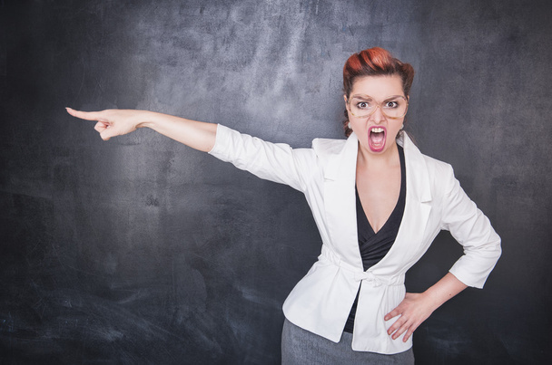 Angry screaming teacher pointing out on blackboard background - Photo, Image