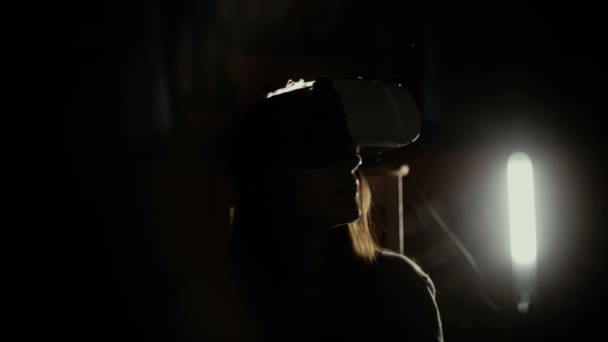 Woman using VR-helmet in the spotlight - Footage, Video