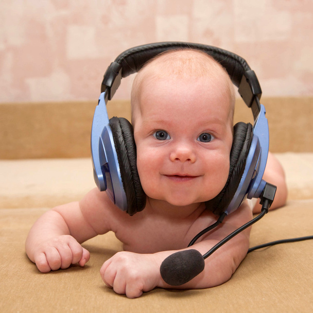 ωραίο νεογέννητο αγοράκι με μπλε μάτια χαμογελώντας φορώντας ένα ακουστικό. - Φωτογραφία, εικόνα