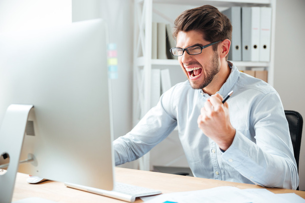 Crazy furious young businessman working and screaming - Foto, imagen
