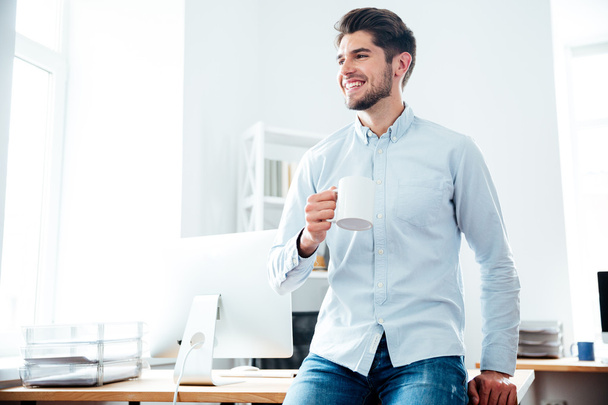 Happy businessman drinking coffee in office - Photo, Image