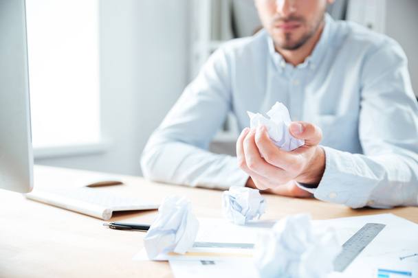 Businessman sitting in office and holding crumpled paper - Фото, зображення