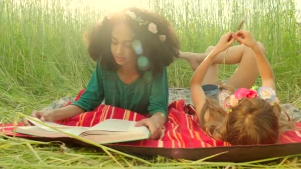 Young girls lying on cover and reading - Footage, Video