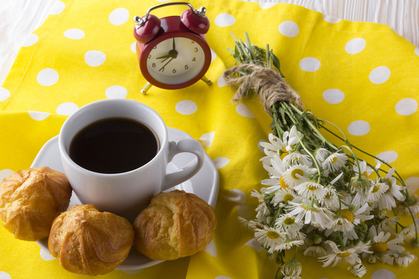 Eclair, koffiekopje, alarm klok en charmomile. - Foto, afbeelding