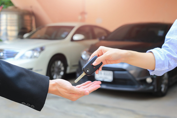 Female hand giving a key for buyer or rental car. - Photo, Image