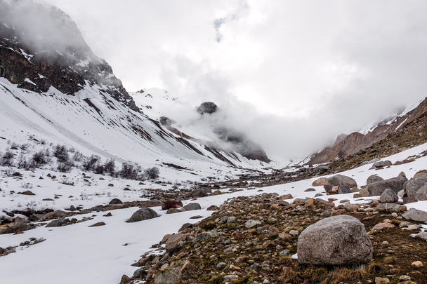 πρωινή ομίχλη των βουνών κοιλάδα με πέτρες και χιόνι - Φωτογραφία, εικόνα