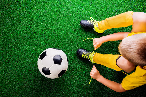 Unrecognizable little football player against green grass, studi - Fotó, kép