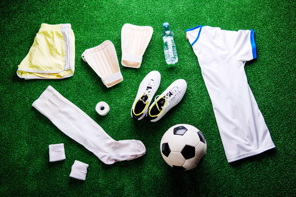 Soccer ball,cleats and various football stuff against artificial - Foto, Imagem