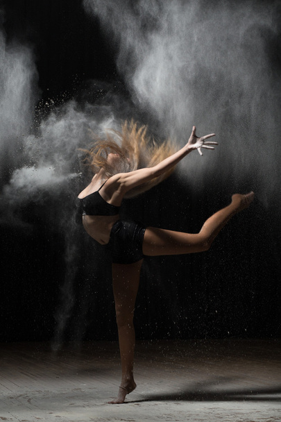 Young ballerina dancing with flour on black background - Fotoğraf, Görsel