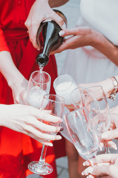 Mooie jonge meisjes in rode jurken vieren een bachelorette partij en drinken champagne - Foto, afbeelding