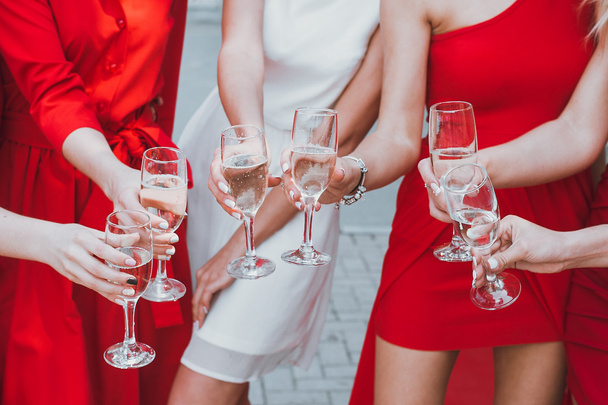 Красивые молодые девушки в красных платьях празднуют девичник и пьют шампанское
 - Фото, изображение