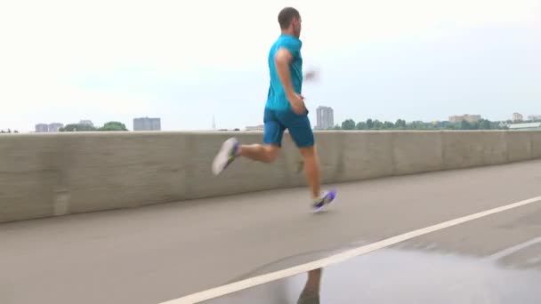 Man in blue uniform running along embankment. Steadicam 4K video - Video