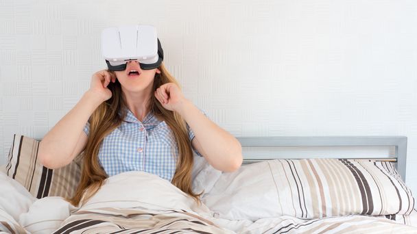 Mulher bonita usando fone de ouvido VR na cama
 - Foto, Imagem