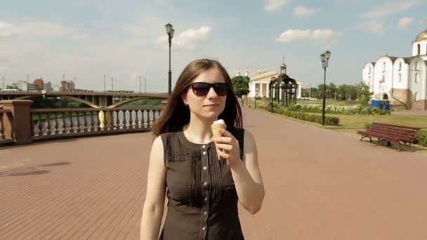 Beautiful woman in sunglasses on street walking and eating ice cream. Steadycam - Video