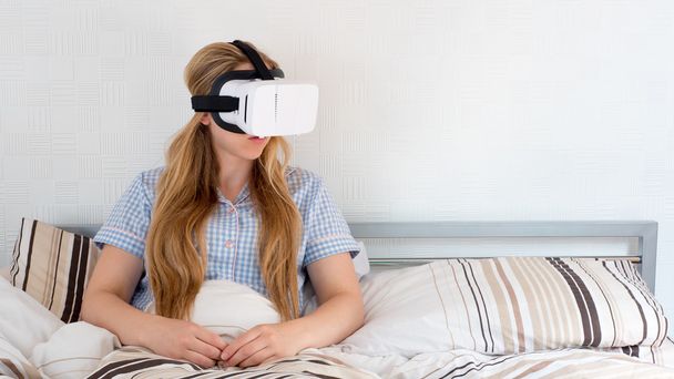 Beautiful woman using VR headset in bed - Photo, Image
