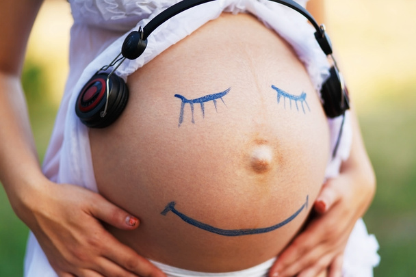 Беременная женщина живот крупным планом с улыбкой смешное лицо
 - Фото, изображение