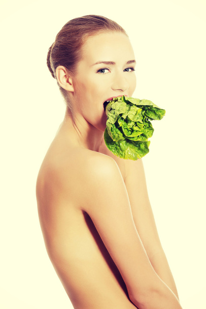 Beautiful woman with fresh green lettuce in mouth. - Photo, image