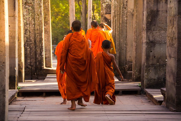 Οι μοναχοί στα αρχαία πέτρα πρόσωπα του ναού Bayon, Angkor - Φωτογραφία, εικόνα