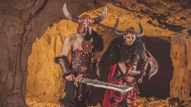 Un par de vikingos en armadura con espadas. Catacumbas en el backgro
 - Foto, Imagen