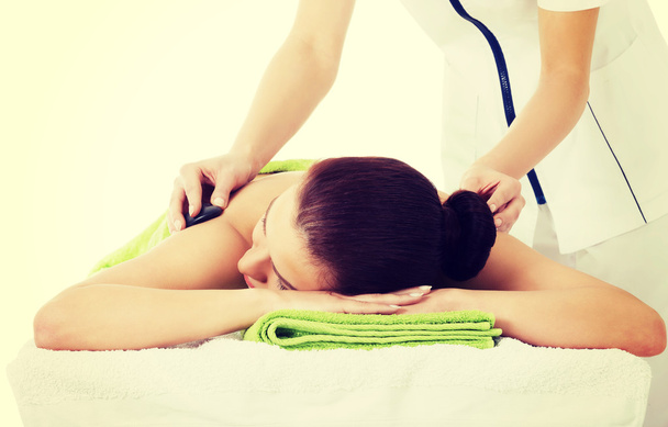 Beautiful woman lying on spa salon having stone massage. - 写真・画像