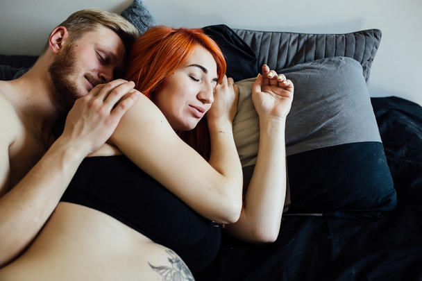 Беременная женщина и мужчина лежат на кровати
 - Фото, изображение