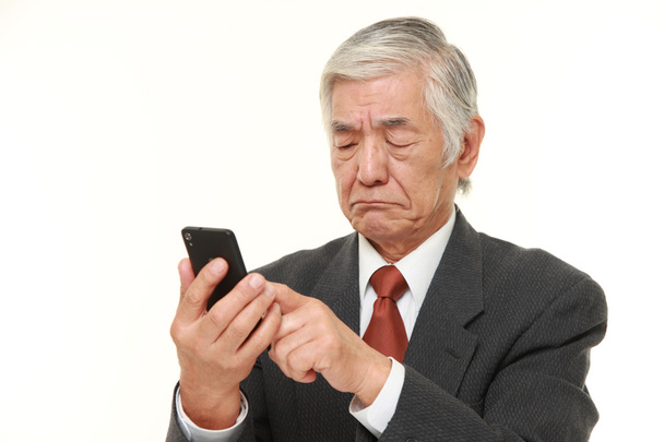 senior Japanese businessman using smart phone looking confused - Photo, Image