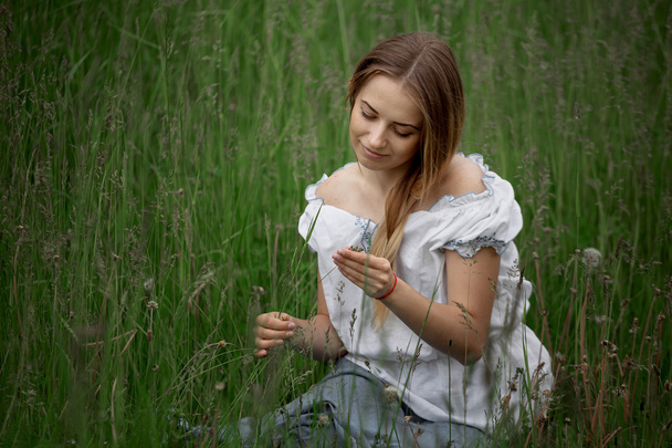 Блондинка в шортах сидит на траве под открытым небом
 - Фото, изображение