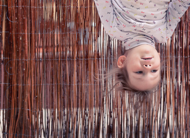 klein meisje hangend ondersteboven - Foto, afbeelding