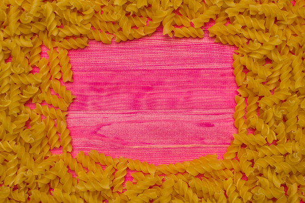 frame of raw pasta on pink wooden plank - Foto, afbeelding