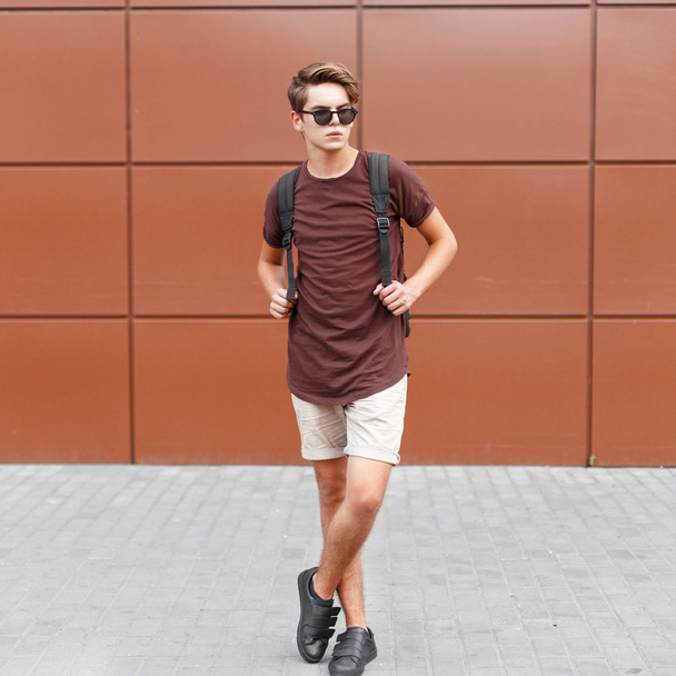 Jonge knappe man in zomer kleding is poseren in de buurt van de muur - Foto, afbeelding