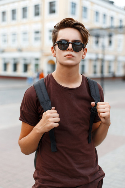 Fiatal jóképű férfi modell úgy néz ki, a napszemüveg, és egy hátizsák utazik. - Fotó, kép