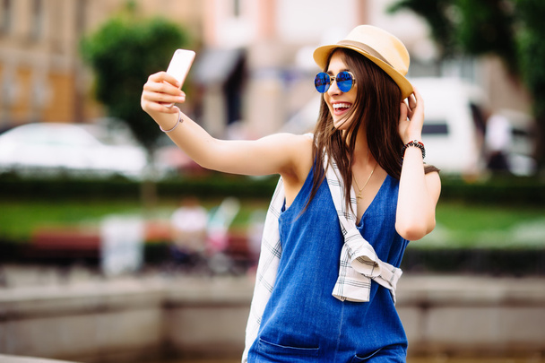 Young smiling teen happy woman making selfie on the street, glasses, traveling alone, having fun, positive mood, joy, vacation, surprised emotions. - Photo, image