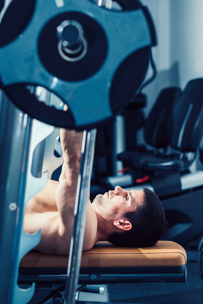 Muscular man lifting weights - Photo, image