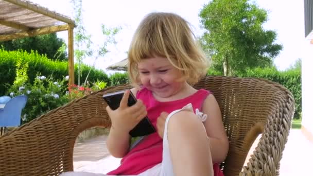 籐の椅子に座って電話を見ている赤ちゃん - 映像、動画