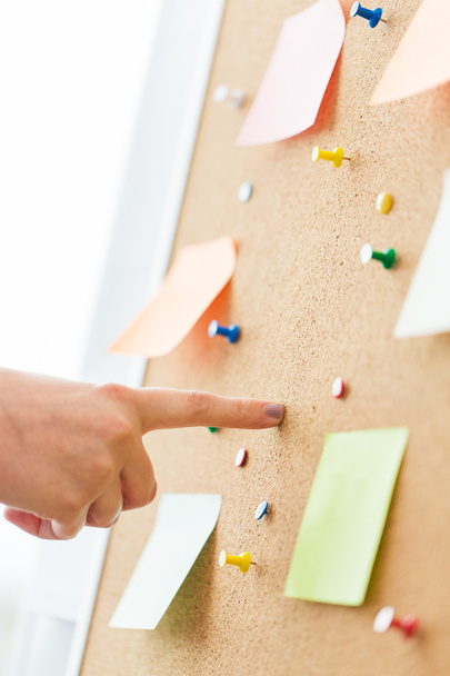 hand pointing to cork board with stickers and pins - Fotografie, Obrázek