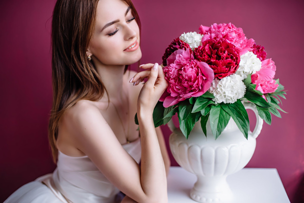 young beautiful bride with a bouquet of pink peony near the wall - Valokuva, kuva