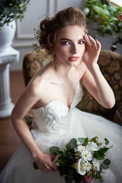 A bride in a beautiful dress holding a bouquet of flowers and greenery. Wedding. wedding bouquet. Bride's morning. Fine art wedding. Happy Bride waiting groom. - Foto, imagen