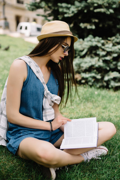 Junge Frau sitzt auf dem Gras und liest das Buch - Foto, Bild