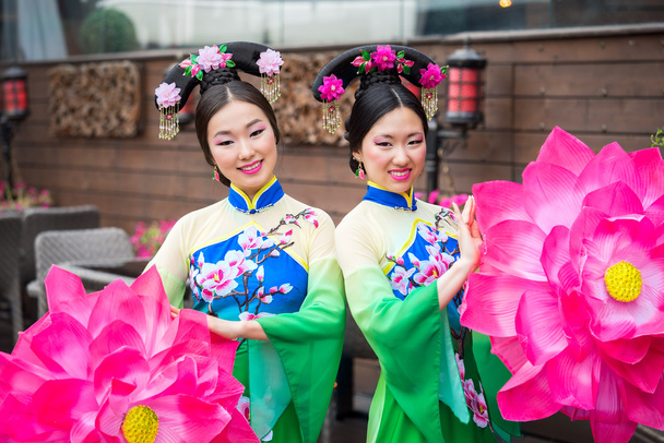 két gyönyörű ázsiai lány hagyományos kínai kék és zöld ruhák, esernyő, lótuszvirág alakjában - Fotó, kép